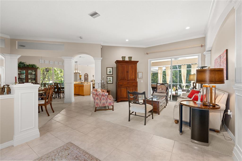 A living room with tile and carpet flooring, a wooden armoire, and sliding glass doors — 8224 WATERVIEW BOULEVARD, LAKEWOOD RANCH, FL