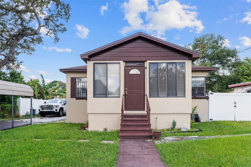 A single-story house with a brown front door, stairs, and large windows under a gable roof — 2708 N MATANZAS AVENUE, TAMPA, FL
