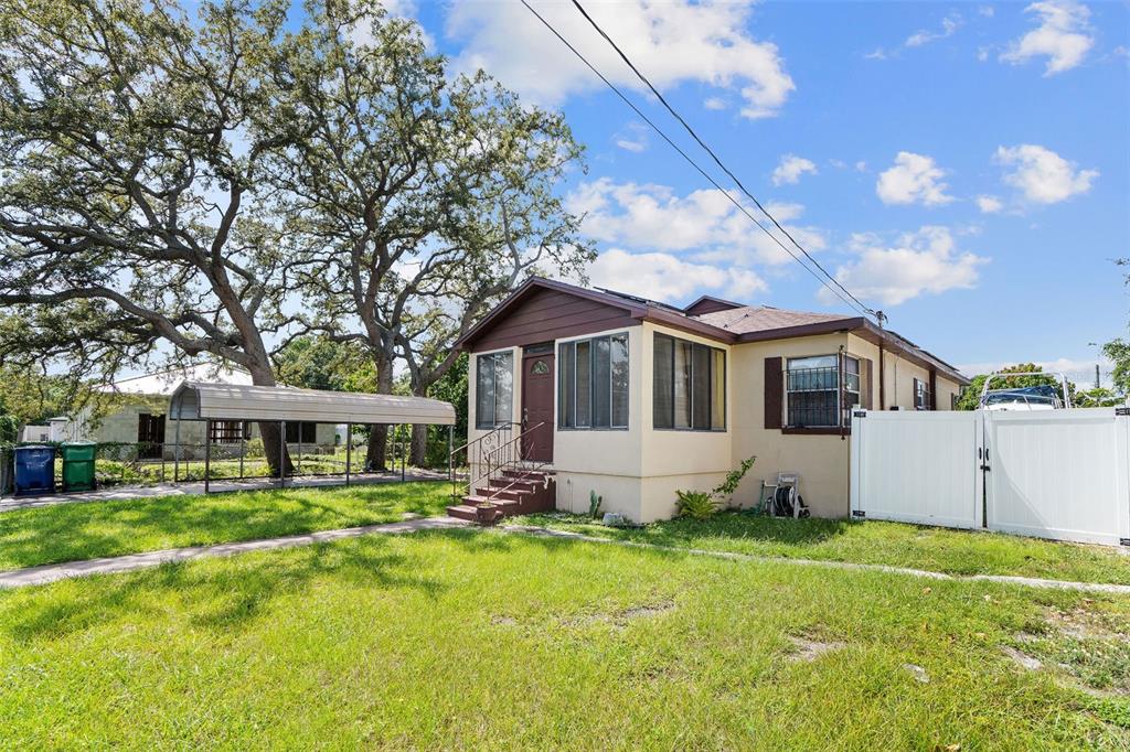 A single-story house with a brown front porch and a white fence on a lawn — 2708 N MATANZAS AVENUE, TAMPA, FL