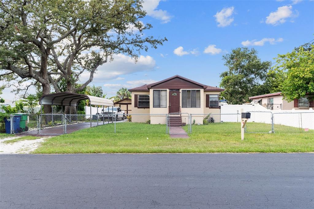 A single-story house with a carport and chain-link fence sits behind a paved road — 2708 N MATANZAS AVENUE, TAMPA, FL