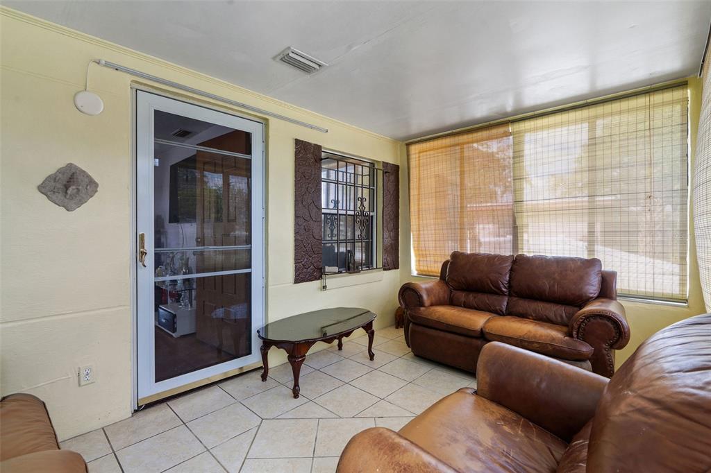 A sunroom features tiled floors, leather furniture, a glass coffee table, and a screen door — 2708 N MATANZAS AVENUE, TAMPA, FL