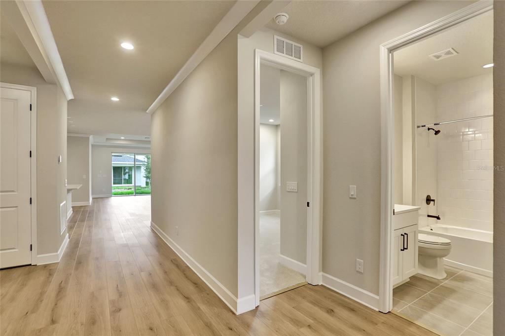 A hallway with light wood flooring leads to a living area, a bedroom, and a bathroom — 3540 STONEBRIAR LANE, SANFORD, FL