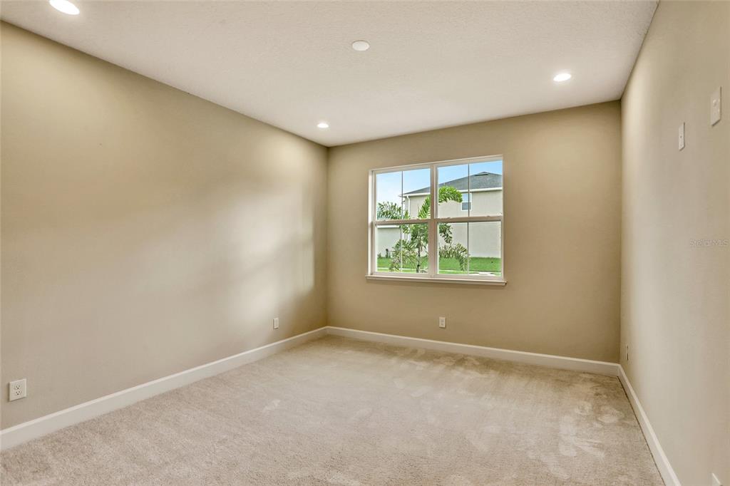 An empty bedroom features beige walls, light-colored carpeting, recessed lighting, and a single window — 3540 STONEBRIAR LANE, SANFORD, FL