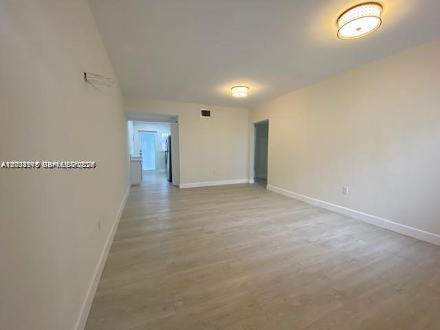 An empty room with light-colored wood-look flooring and two ceiling-mounted light fixtures — 3530 SW 9th Ter # 6B, Miami FL 33135, MIAMI, FL