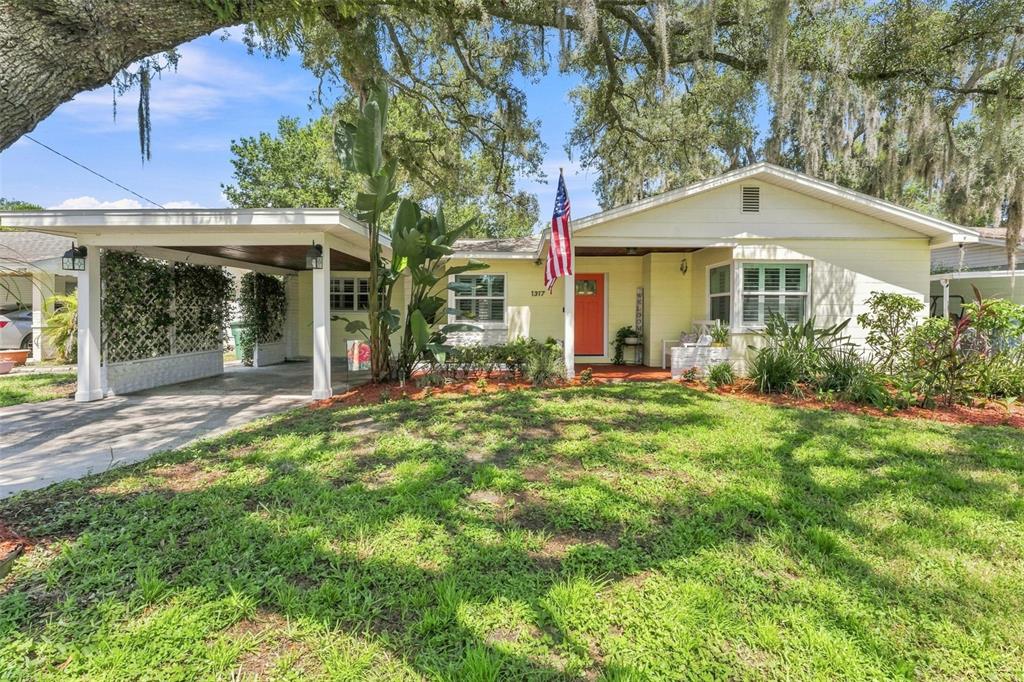 A single-story house with a carport, a bright orange front door, and a large oak tree — 1317 DIVOT LANE, TAMPA, FL