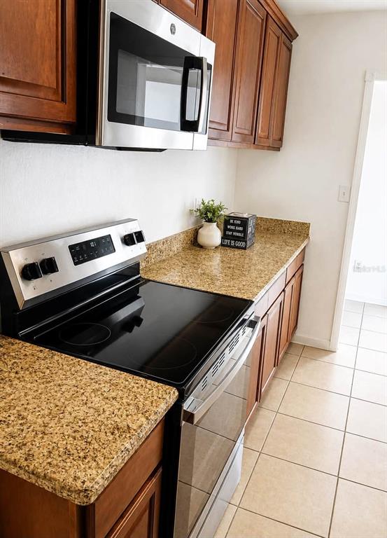A kitchen features wooden cabinets, stainless steel appliances, and speckled granite countertops — 208 PALMYRA DRIVE, ORLANDO, FL