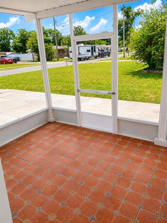 A screened-in porch features orange patterned tile flooring and a view of a residential street — 208 PALMYRA DRIVE, ORLANDO, FL