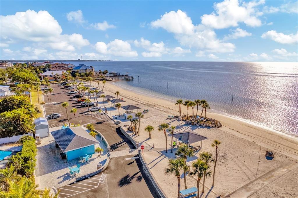 An aerial view shows a sandy beach with palm trees, picnic shelters, and a parking lot — 21 WESTSHORE DRIVE, NEW PORT RICHEY, FL