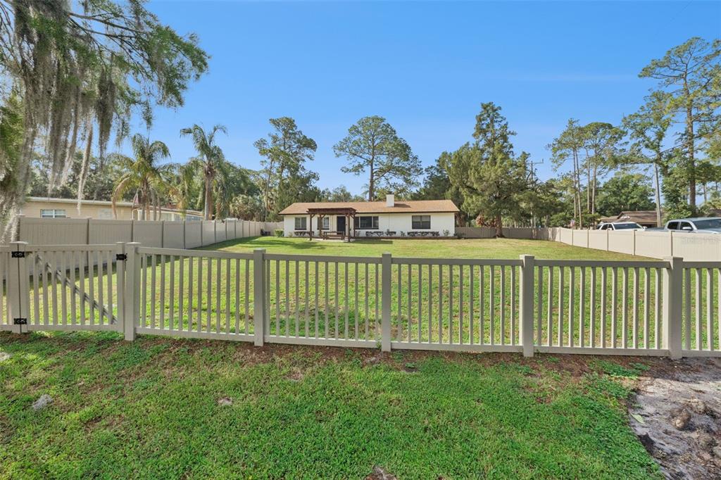 A fenced backyard with a grassy lawn and a single-story house in the background — 219 S CRYSTAL DRIVE, SANFORD, FL