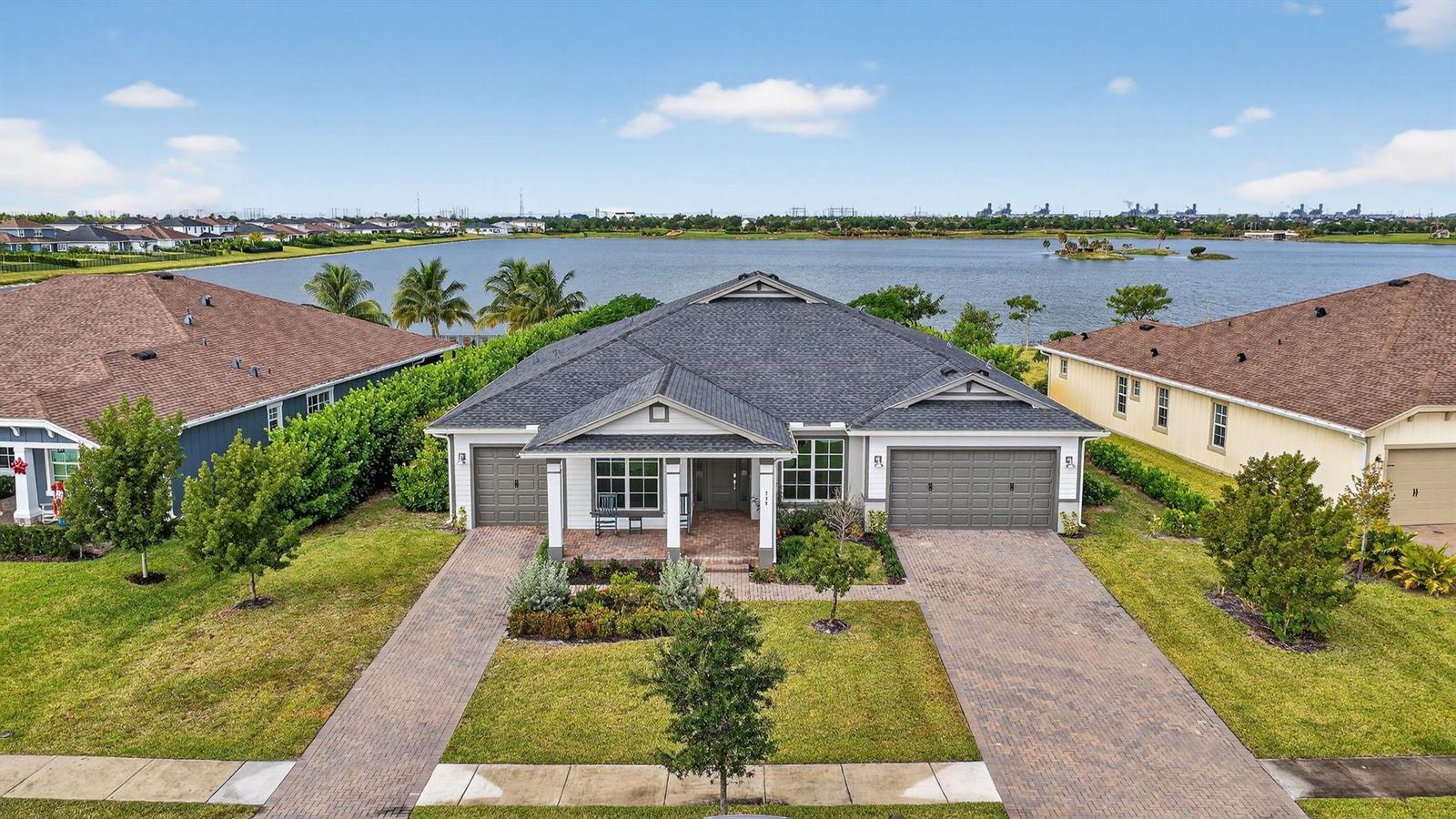 An aerial view of a single-story house with a brick driveway facing a large lake — 799 Hookline Circle, Loxahatchee FL 33470, LOXAHATCHEE, FL