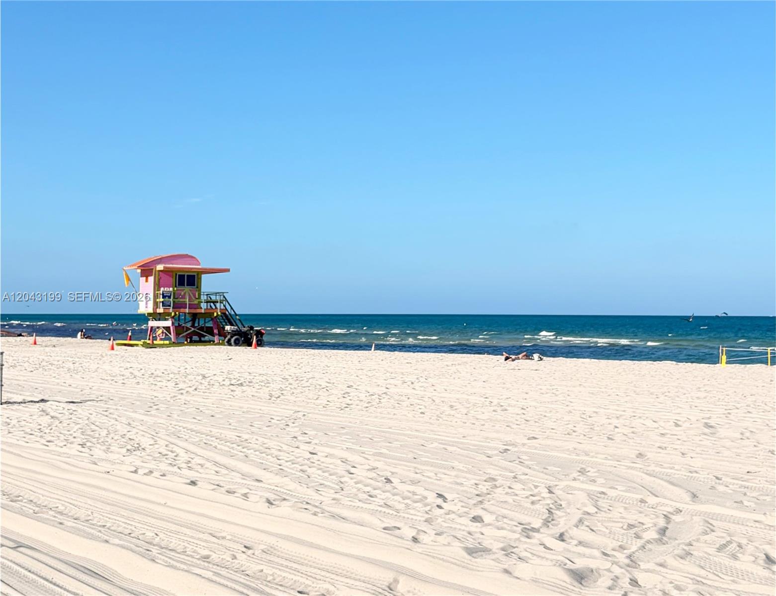 A colorful lifeguard stand sits on a wide, sandy beach under a clear blue sky — 2625 Collins Ave # 215, Miami Beach FL 33140, MIAMI BEACH, FL