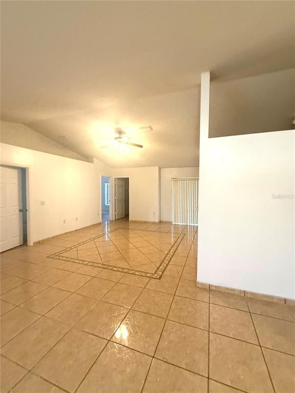 An open living area features light-colored tile flooring with a decorative inlay and vaulted ceilings — 1011 CANNES DRIVE, KISSIMMEE, FL