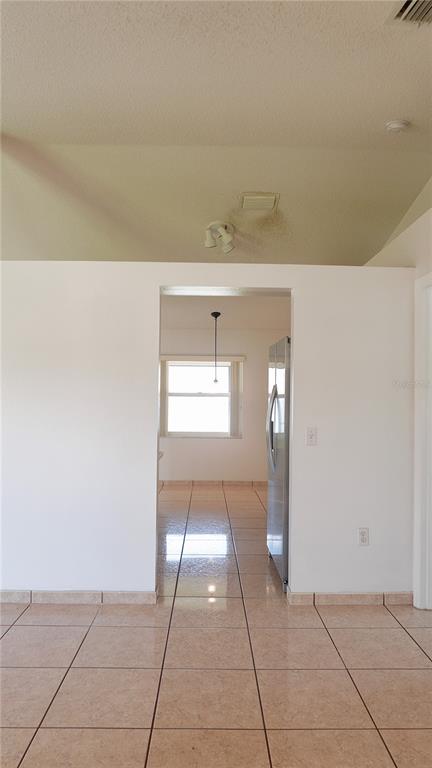 A view through a doorway shows a kitchen with tile flooring and a window — 1011 CANNES DRIVE, KISSIMMEE, FL