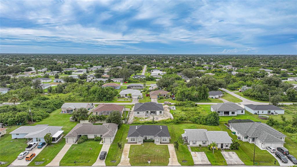 An aerial view shows several single-family homes surrounded by green lawns and dense vegetation — 11057 & 11059 PENDLETON AVENUE, ENGLEWOOD, FL