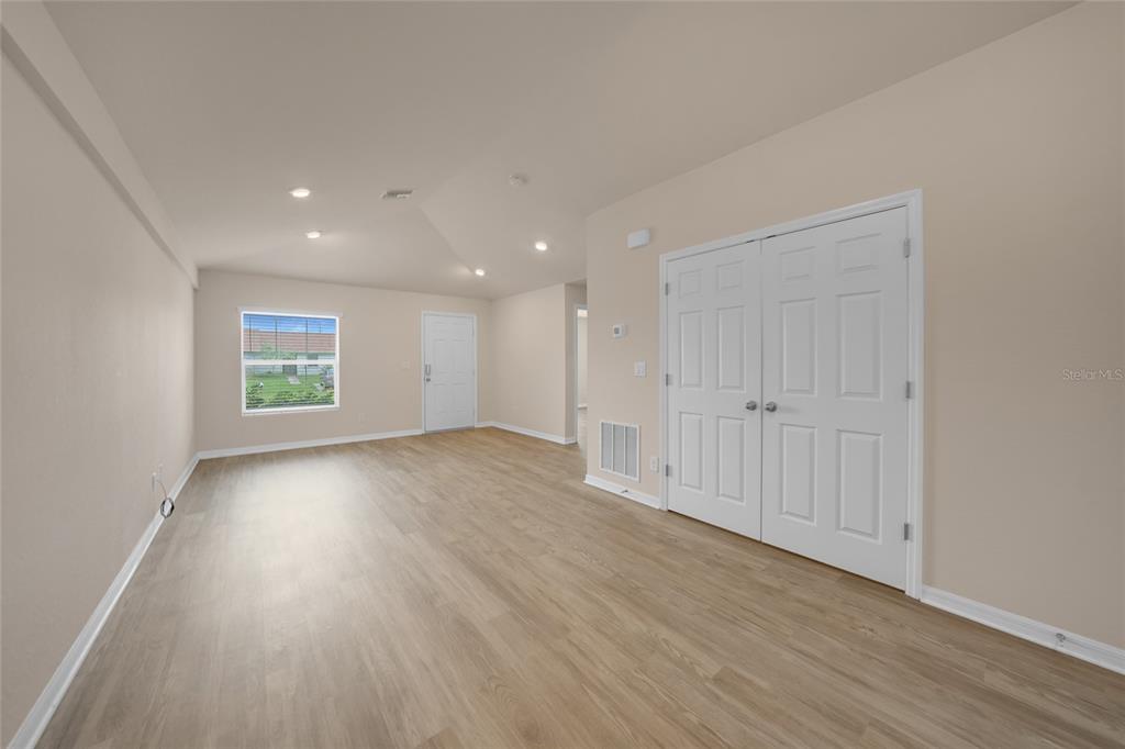 A room with light-colored walls, wood-look flooring, a window, and a set of double doors — 11057 & 11059 PENDLETON AVENUE, ENGLEWOOD, FL