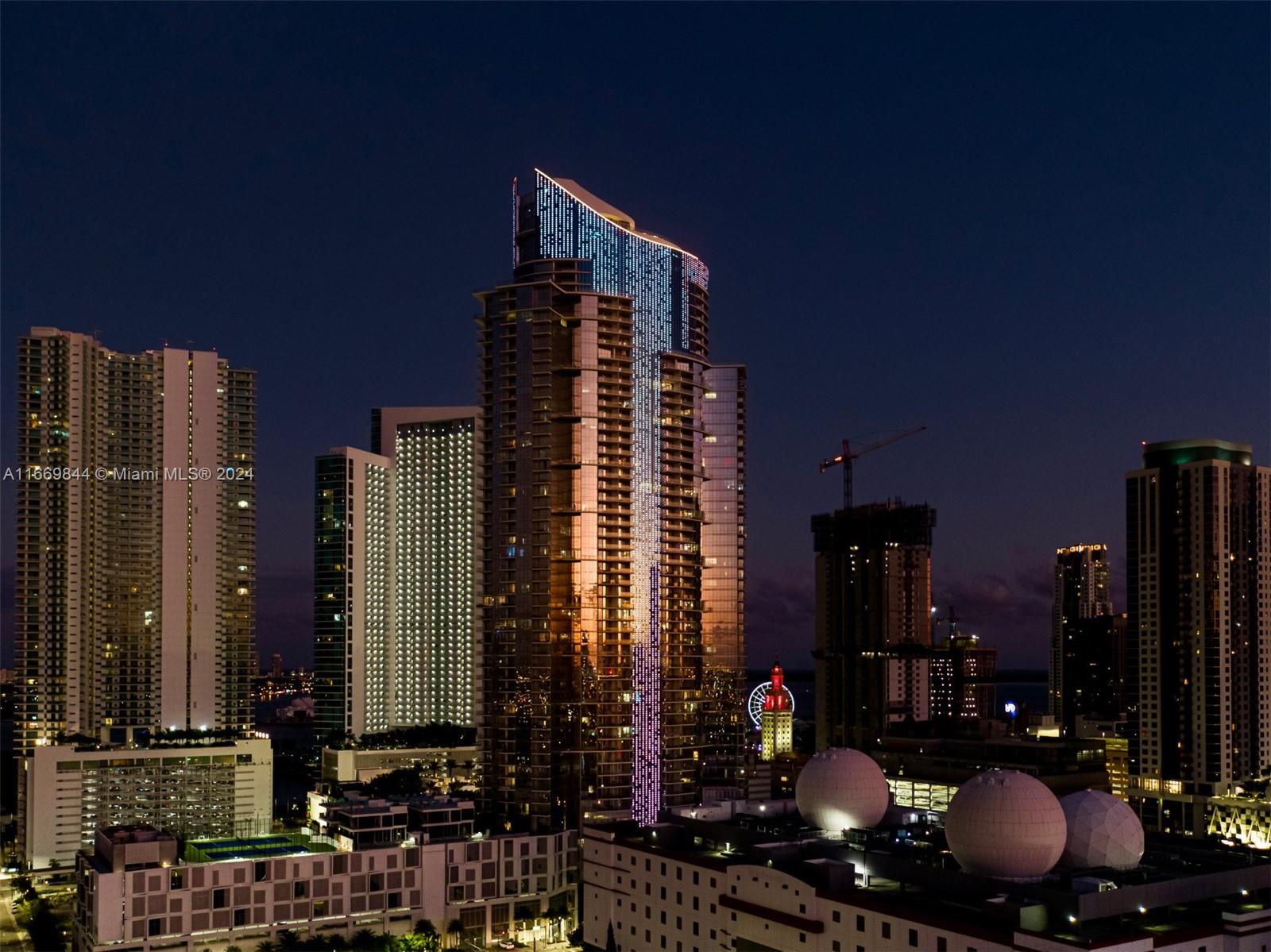 An exterior night view of a Miami skyline featuring a prominent illuminated skyscraper — 851 NE 1st Ave # 5412, Miami FL 33132, MIAMI, FL