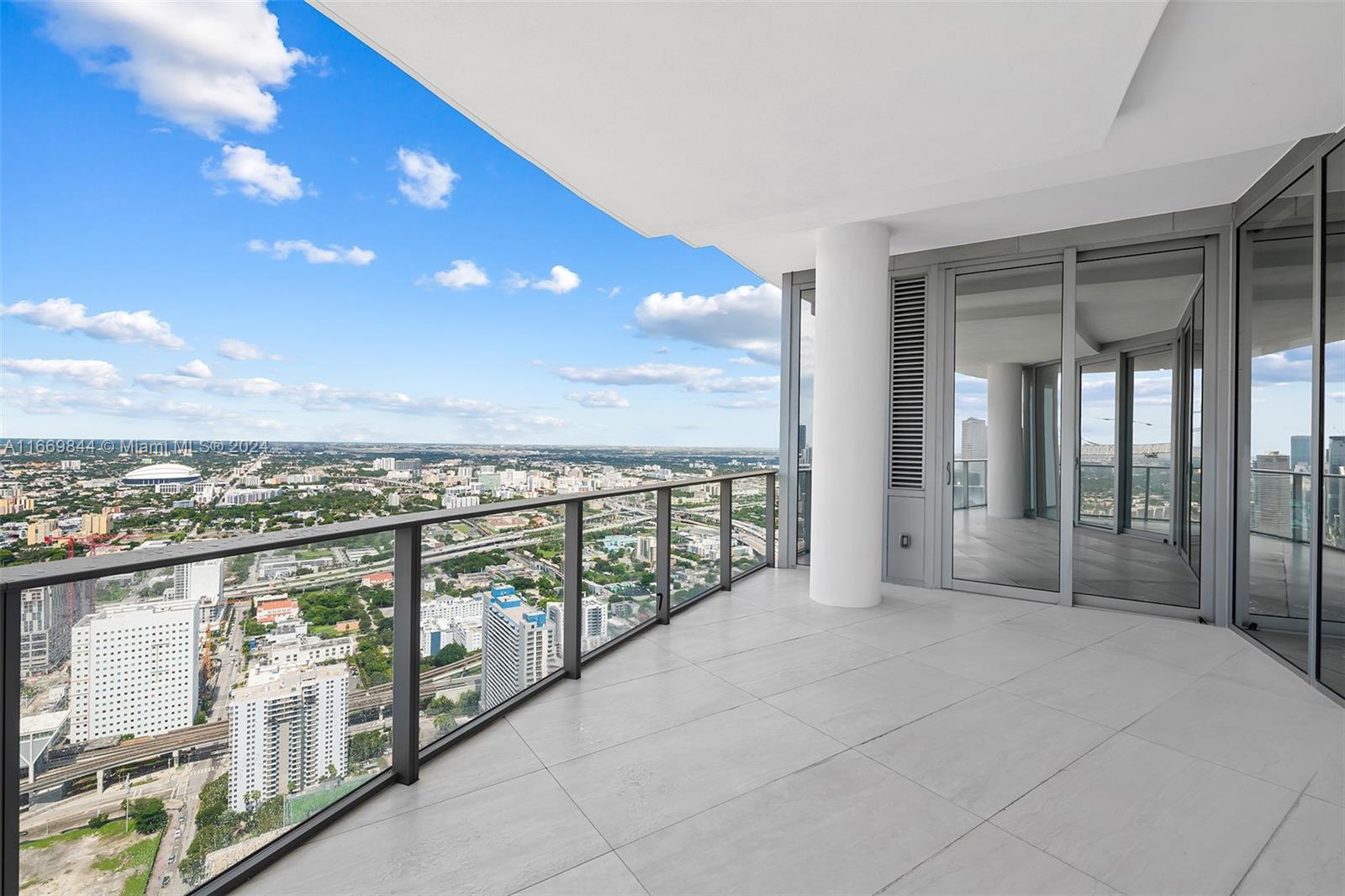 A high-rise balcony with glass railings overlooks a city skyline under a blue sky — 851 NE 1st Ave # 5412, Miami FL 33132, MIAMI, FL