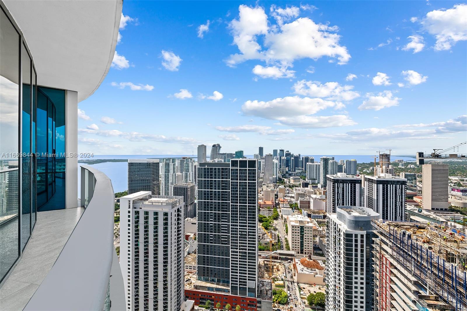 A high-rise balcony overlooks a dense urban skyline and a large body of water — 851 NE 1st Ave # 5412, Miami FL 33132, MIAMI, FL