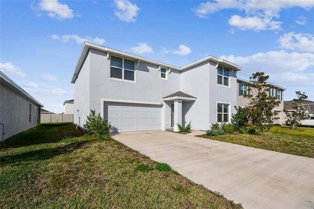 A two-story house with a light gray exterior, a single-car garage, and a concrete driveway — 9208 MISSION BAY PLACE, TAMPA, FL