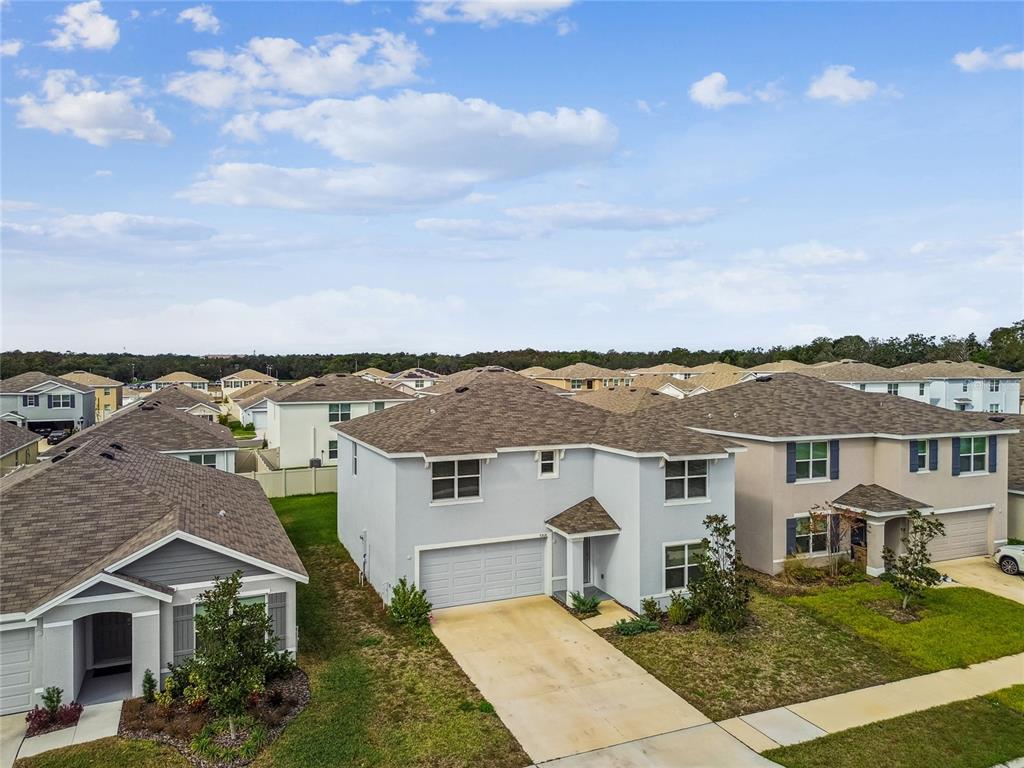 An aerial view shows a two-story suburban house with a gray exterior and concrete driveway — 9208 MISSION BAY PLACE, TAMPA, FL