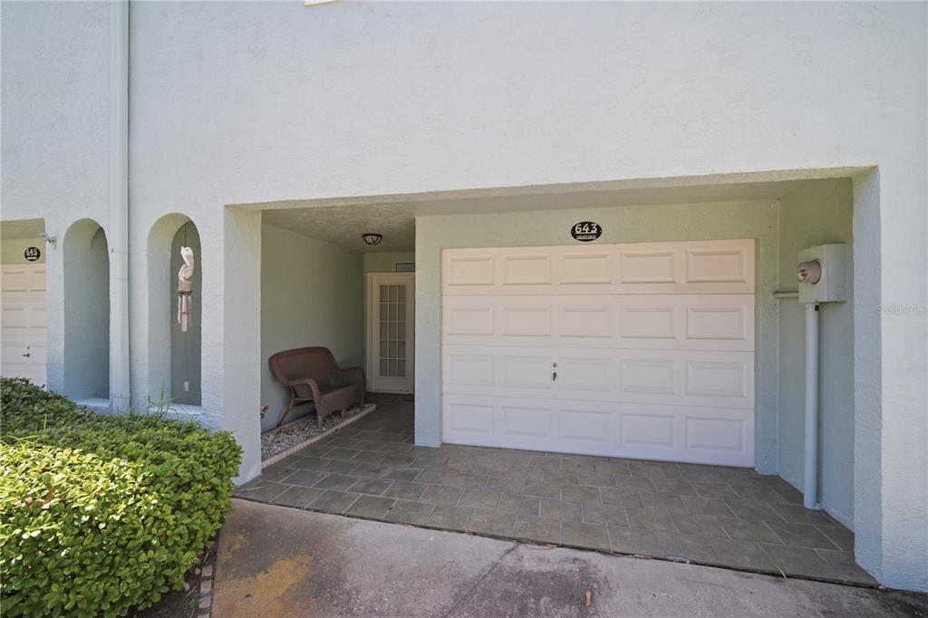 A light-colored building exterior features a single-car garage, a covered entryway, and a small bench — 643 GARLAND CIRCLE, INDIAN ROCKS BEACH, FL