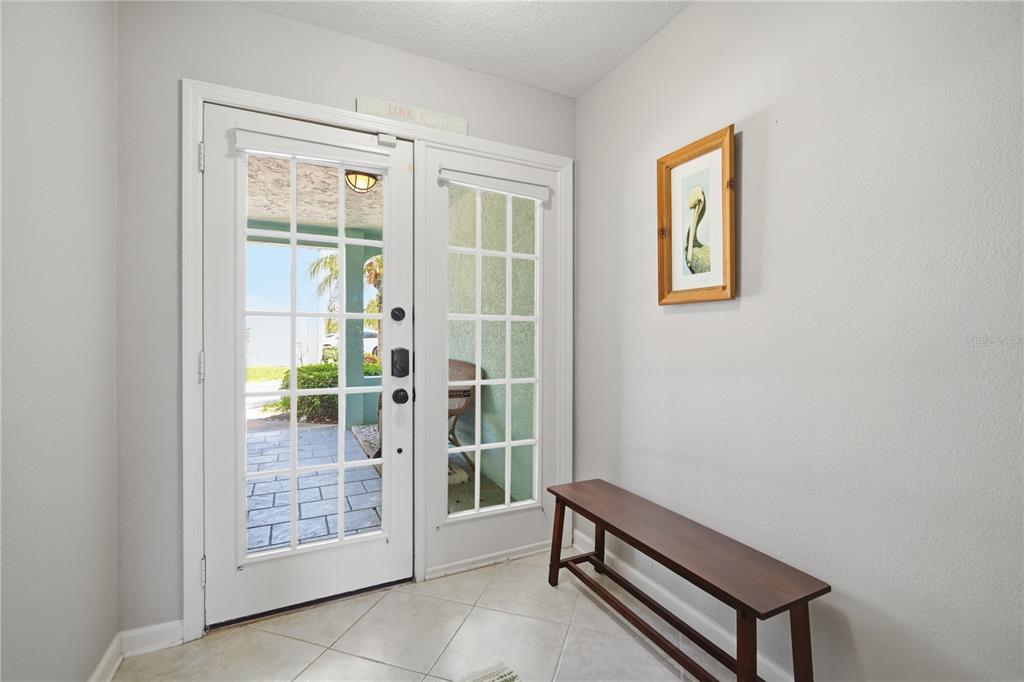 An entryway features a double glass door, a wooden bench, and a framed wall picture — 643 GARLAND CIRCLE, INDIAN ROCKS BEACH, FL