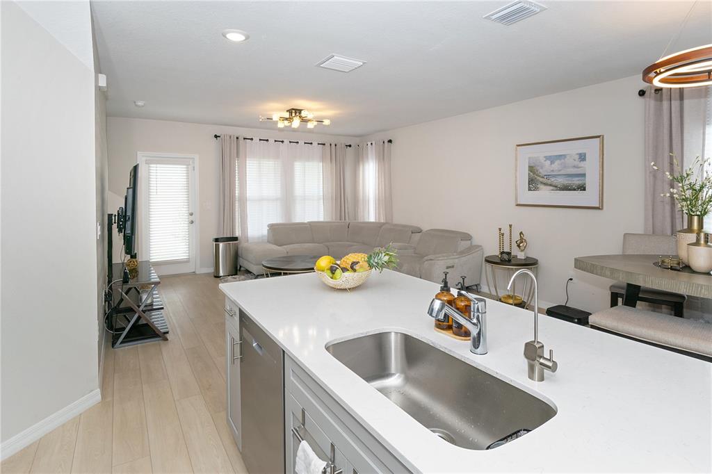 A kitchen island with a stainless steel sink overlooks a living room and dining area — 3798 KING HILL DRIVE, HAINES CITY, FL