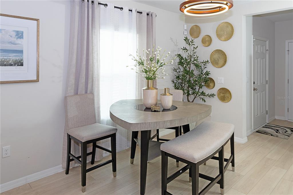 A dining area features a triangular table, two chairs, a bench, and gold wall decor — 3798 KING HILL DRIVE, HAINES CITY, FL