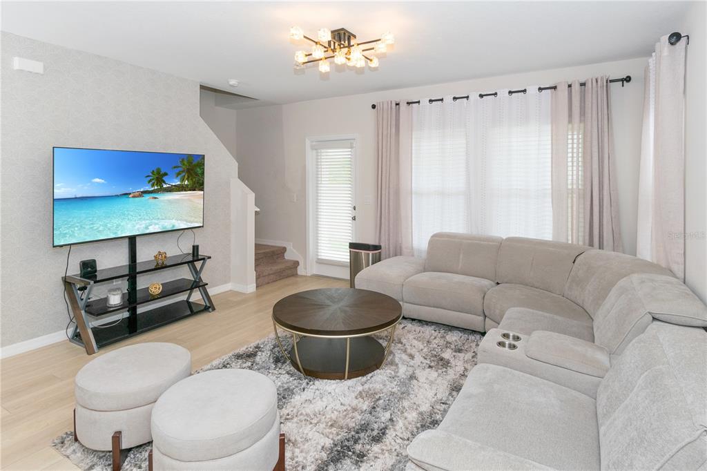 A living room features a sectional sofa, round coffee table, television, and light wood flooring — 3798 KING HILL DRIVE, HAINES CITY, FL