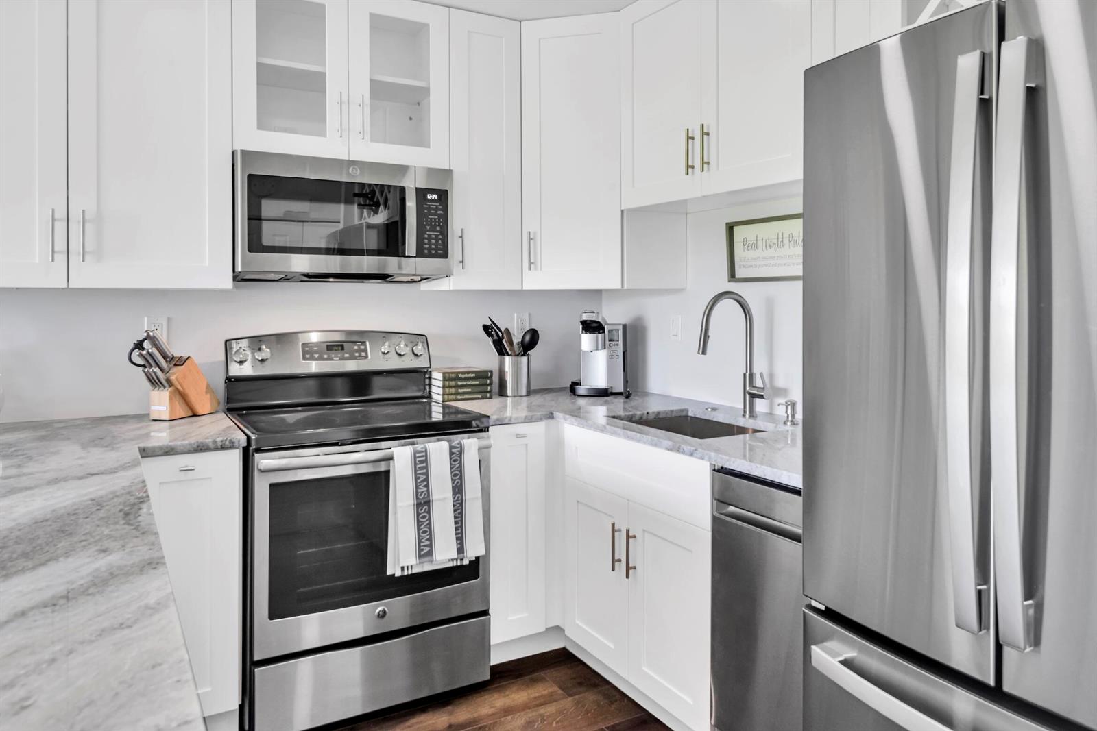 A bedroom features a black bed frame, matching nightstands, gray bedding, and dark wood flooring — 401 Greensward Lane # a, Delray Beach FL 33445, DELRAY BEACH, FL