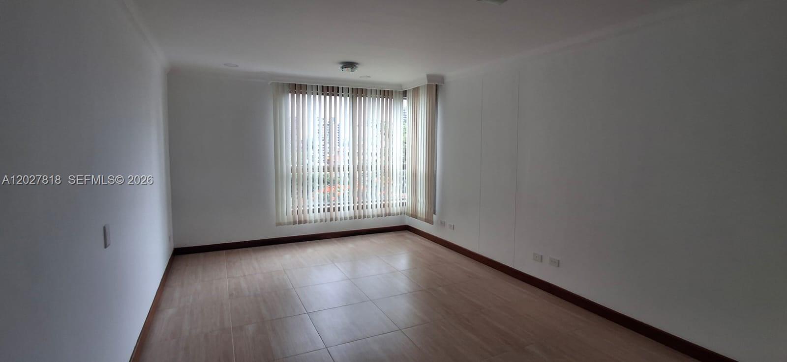 An empty room features light-colored tile flooring, white walls, and vertical blinds over a window — Cra 15 4 28 # 401, 0, FL
