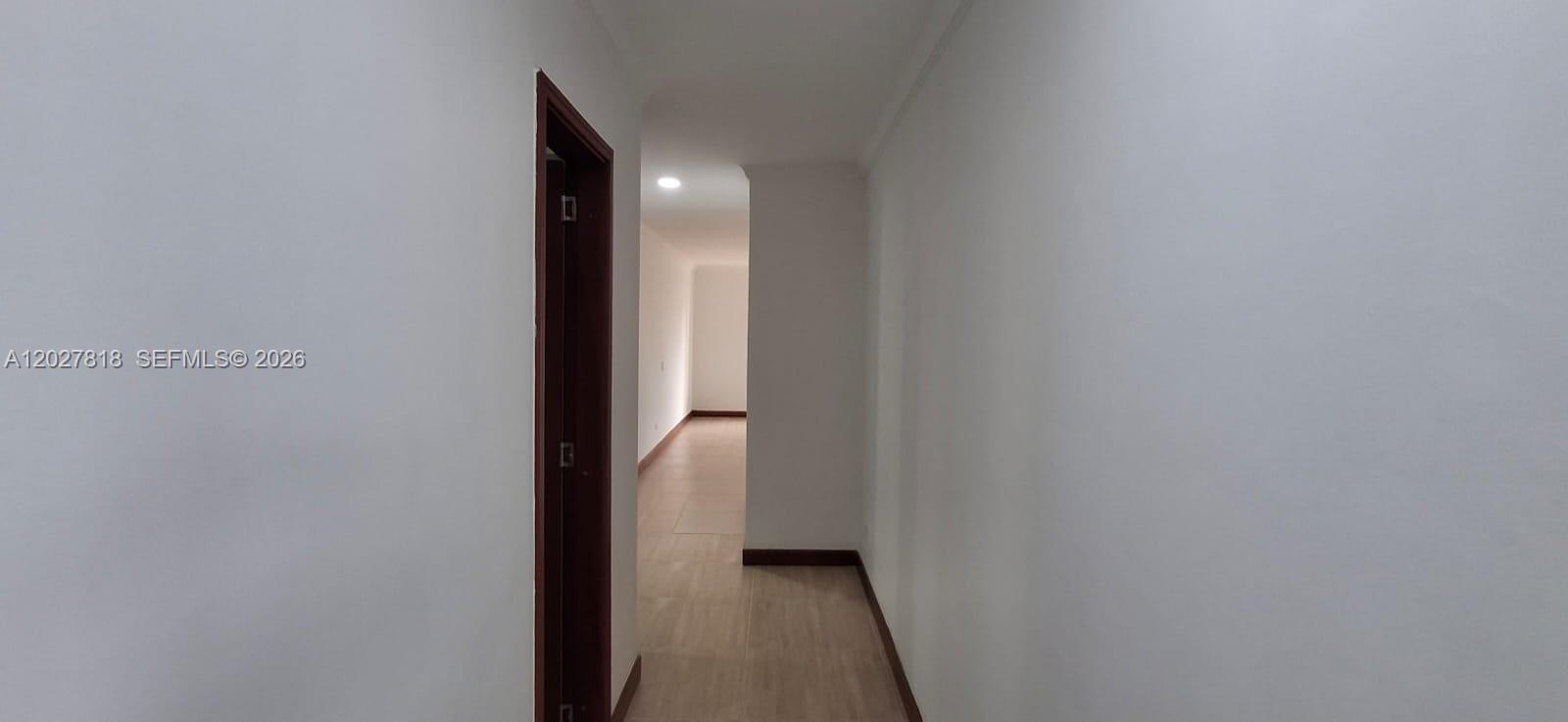 A hallway with light wood-look flooring leads to an open room with white walls — Cra 15 4 28 # 401, 0, FL