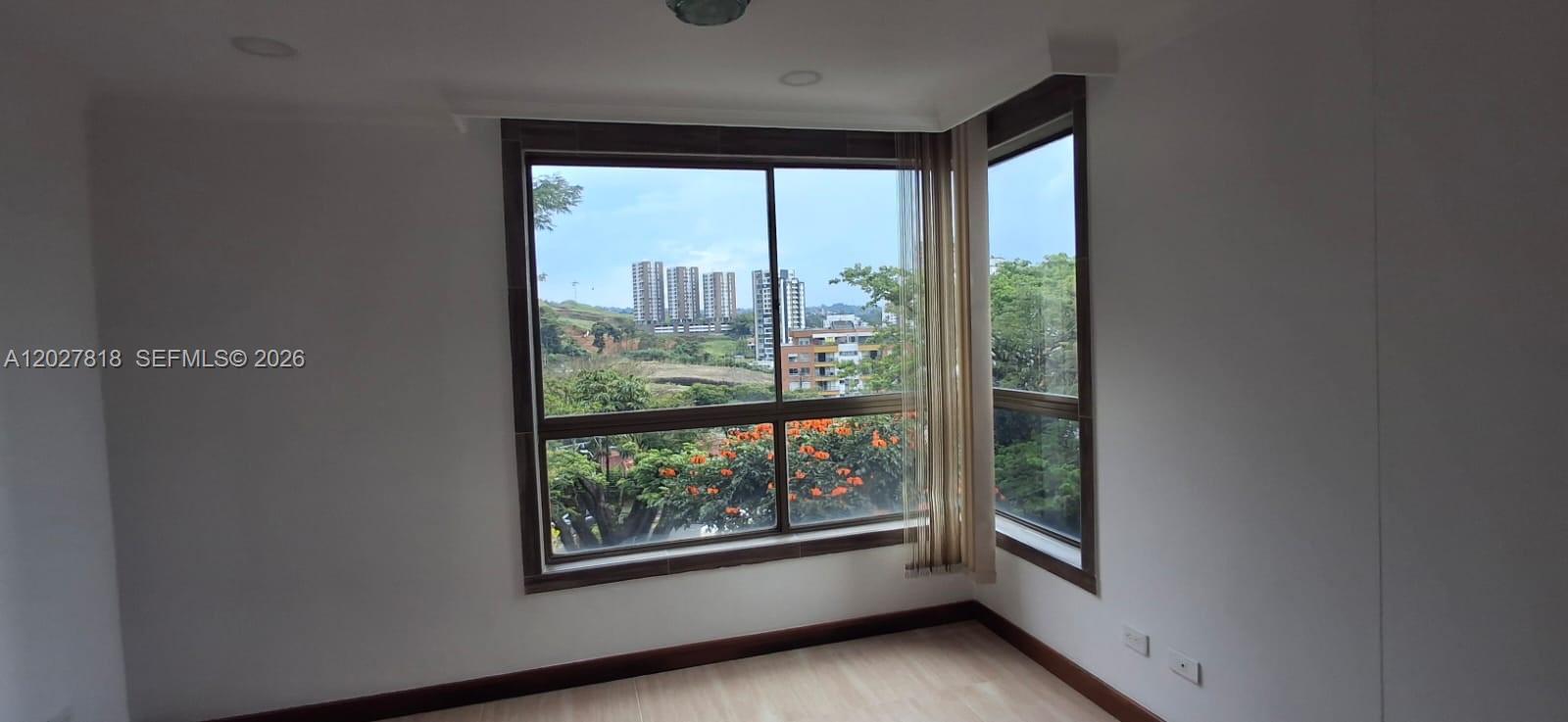 An empty room features light wood flooring, white walls, and large corner windows with views — Cra 15 4 28 # 401, 0, FL