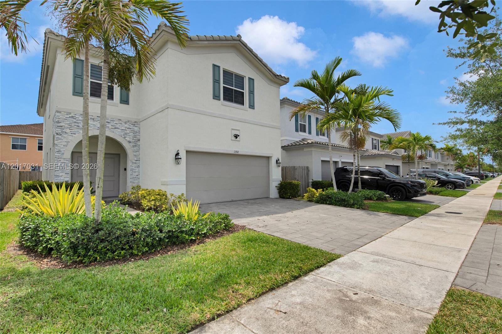 A two-story suburban house features a stone-accented entryway, a garage, and palm trees — 1392 SE 26th Ter, Homestead FL 33035, HOMESTEAD, FL