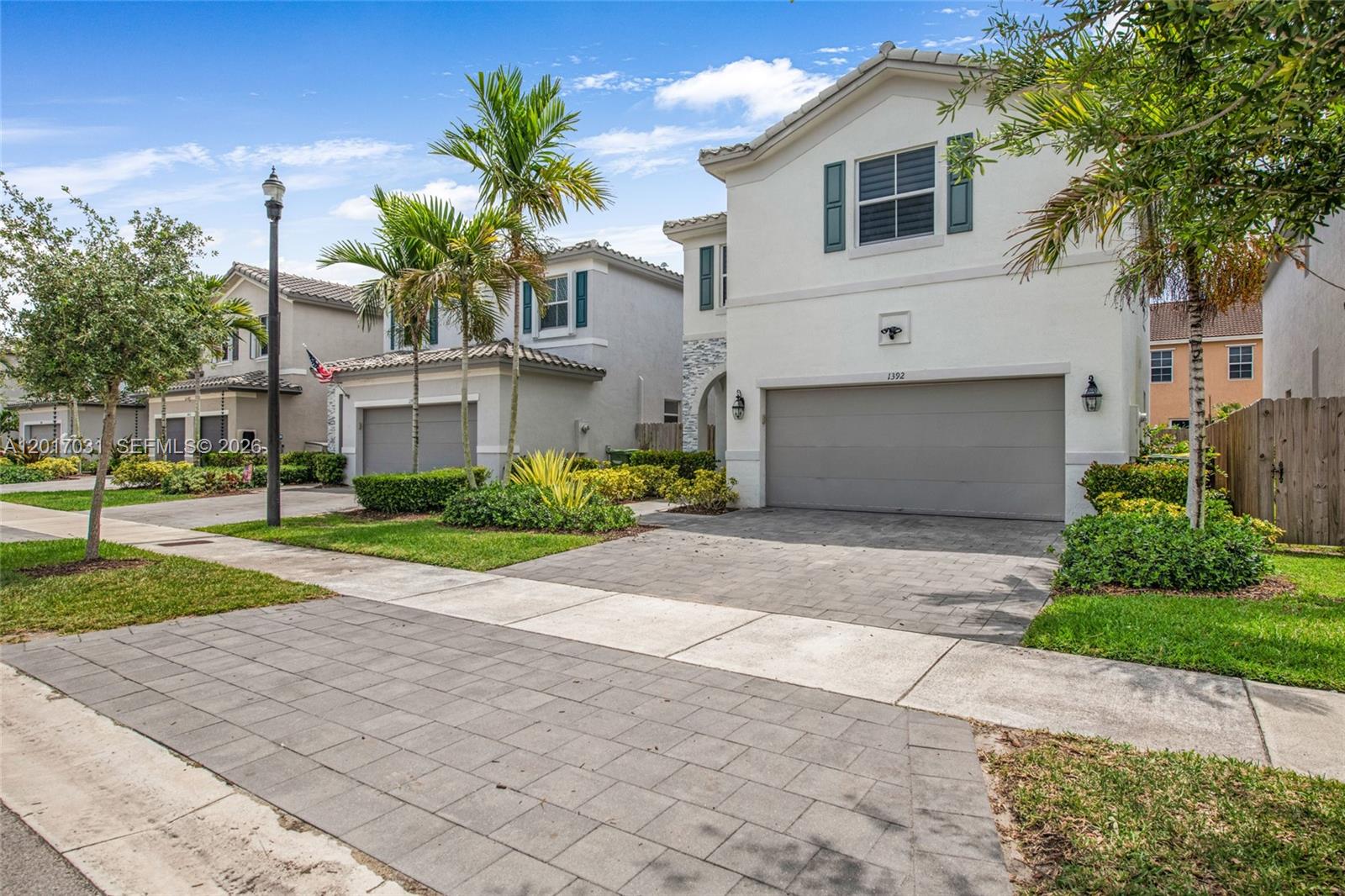 A two-story suburban house with a paved driveway, a two-car garage, and palm trees — 1392 SE 26th Ter, Homestead FL 33035, HOMESTEAD, FL