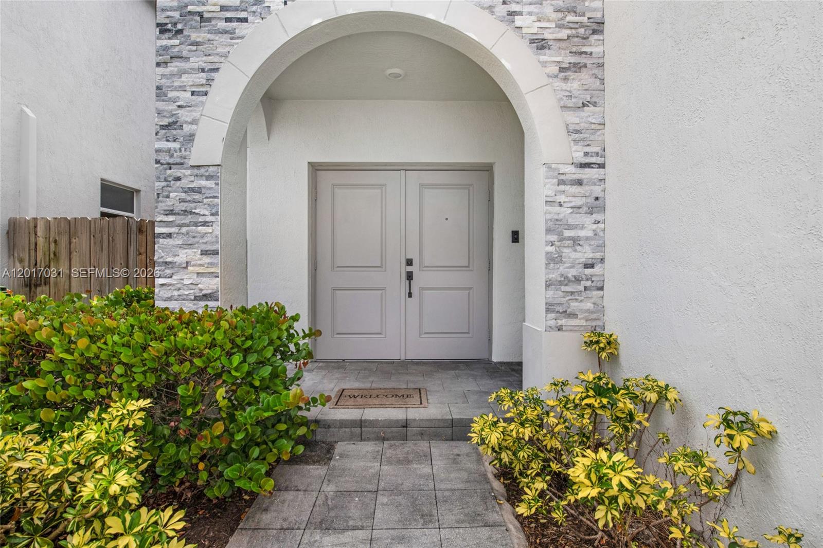 The exterior entrance features a stone-accented arched doorway with double doors and a walkway — 1392 SE 26th Ter, Homestead FL 33035, HOMESTEAD, FL