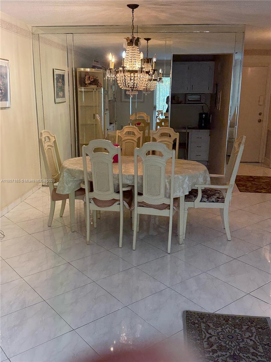 A dining room features a chandelier, a table with six chairs, and mirrored walls — 1395 NE 167th St # 203, Miami FL 33162, MIAMI, FL
