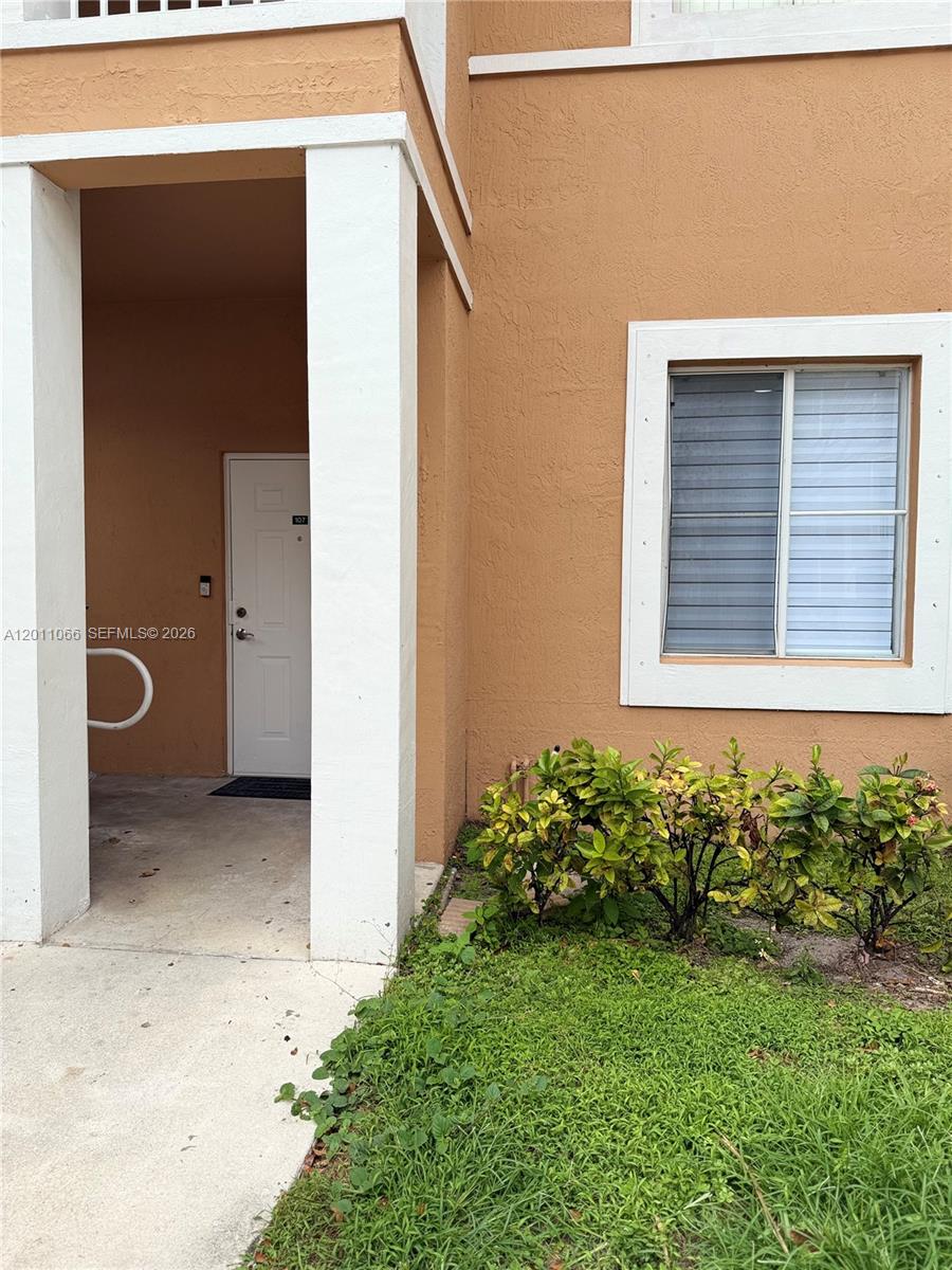 The exterior of a tan building features a covered entryway with a white door — 7070 NW 177th St # 10, Hialeah FL 33015, HIALEAH, FL