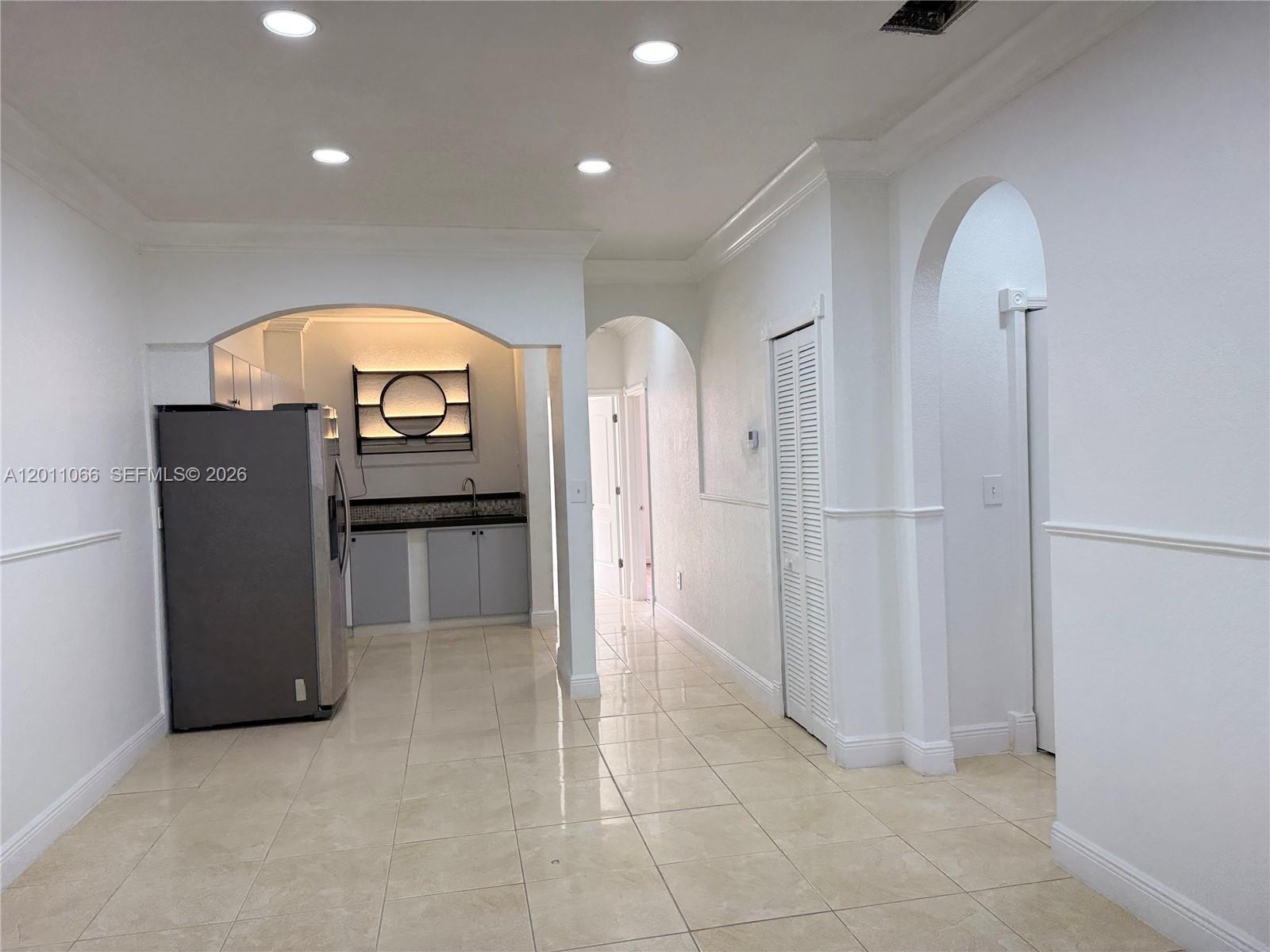 A kitchen area with a refrigerator and cabinets is visible through an arched entryway — 7070 NW 177th St # 10, Hialeah FL 33015, HIALEAH, FL