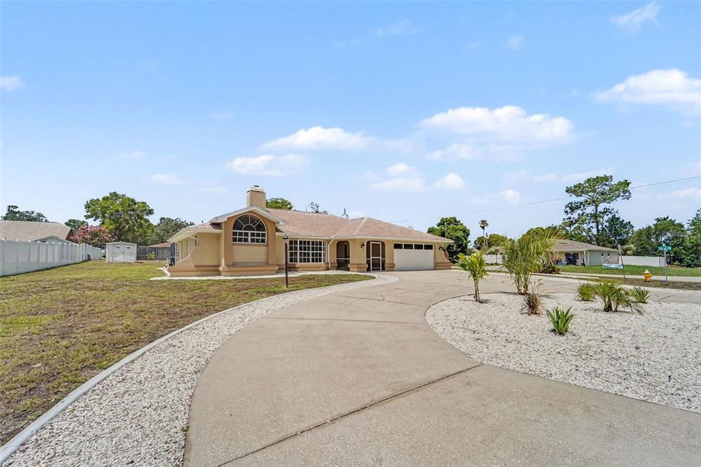 A single-story house with a curved concrete driveway and a white gravel front yard — 8500 BAY DRIVE, SPRING HILL, FL
