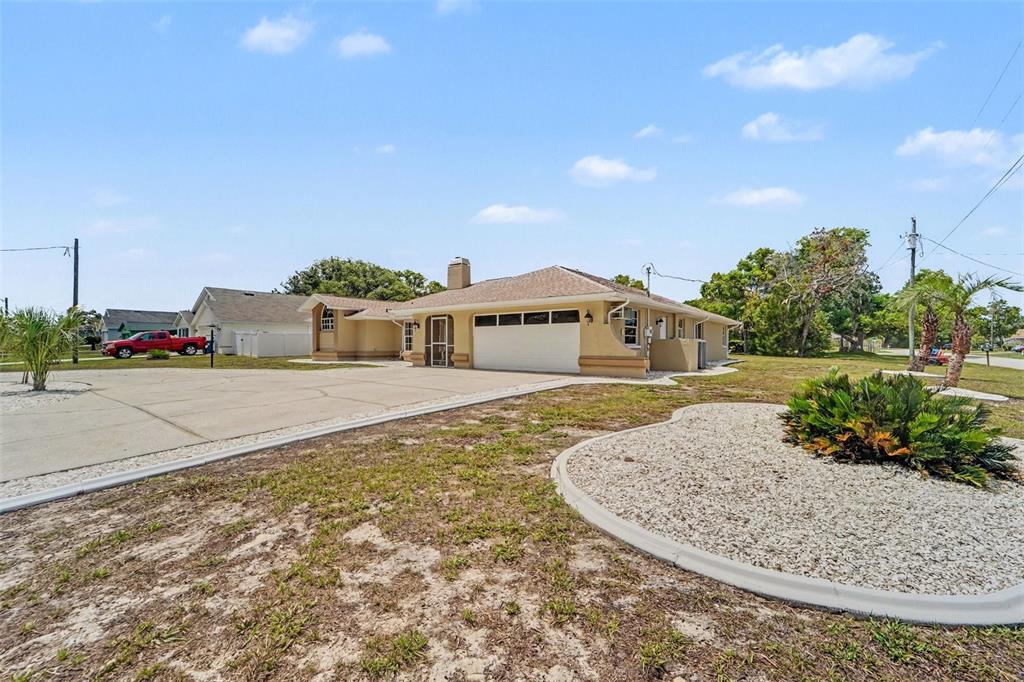 A tan single-story house with a large concrete driveway and a white garage door — 8500 BAY DRIVE, SPRING HILL, FL