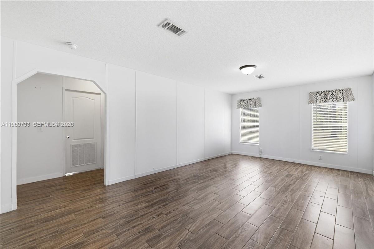 An empty room features white walls, wood-look flooring, and two windows with patterned valances — 415 S Kennel St, Clewiston FL 33440, CLEWISTON, FL