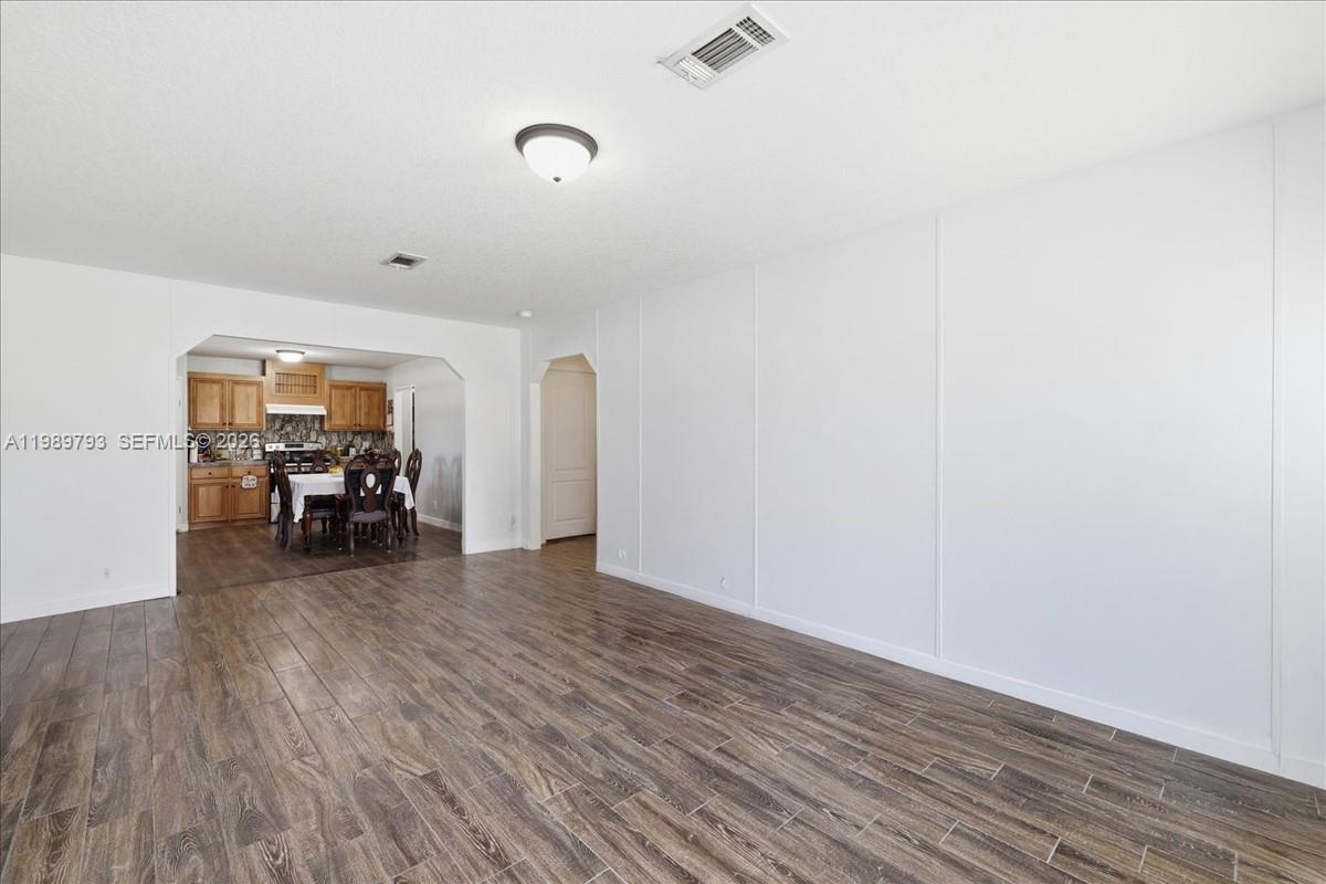 A living room with wood-look tile flooring leads into an adjacent dining area and kitchen — 415 S Kennel St, Clewiston FL 33440, CLEWISTON, FL