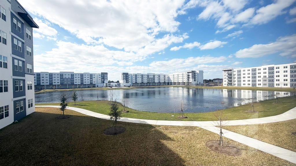 An exterior view of modern apartment buildings surrounding a central pond with a walking path — 5587 MILLENIA BOULEVARD UNIT 213, ORLANDO, FL
