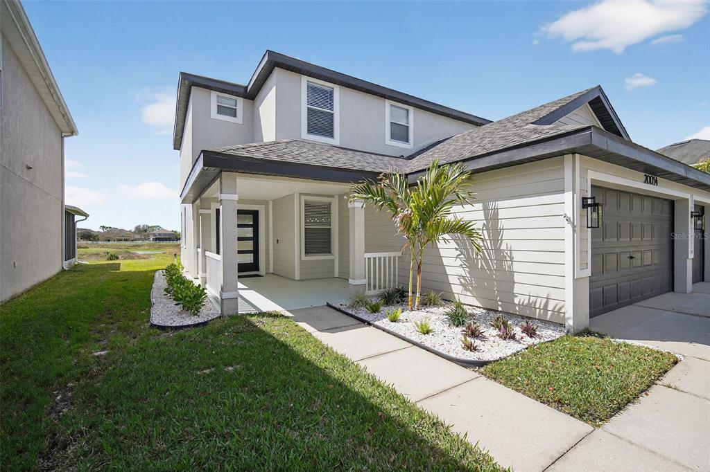 A two-story house with a covered front porch, gray siding, and a concrete walkway — 20054 NOB OAK AVENUE, TAMPA, FL