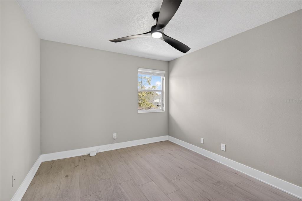 An empty bedroom features light gray walls, wood-look flooring, and a modern ceiling fan — 20054 NOB OAK AVENUE, TAMPA, FL