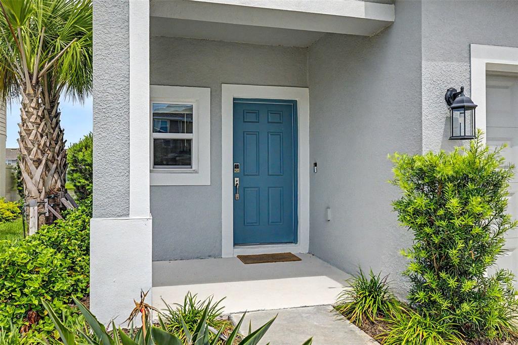 A two-story gray townhouse with a blue front door and a concrete driveway — 2307 PARAVANE WAY, WESLEY CHAPEL, FL