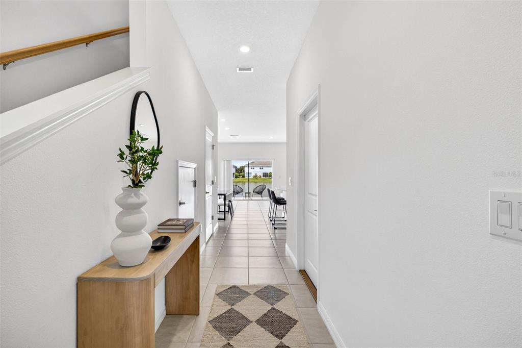 A blue front door is centered on a covered porch with a window and landscaping — 2307 PARAVANE WAY, WESLEY CHAPEL, FL
