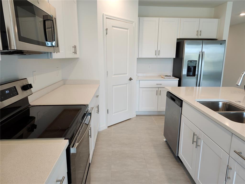 A modern kitchen features white cabinets, stainless steel appliances, and light-colored countertops — 1009 CALICO POINTE CIRCLE, GROVELAND, FL