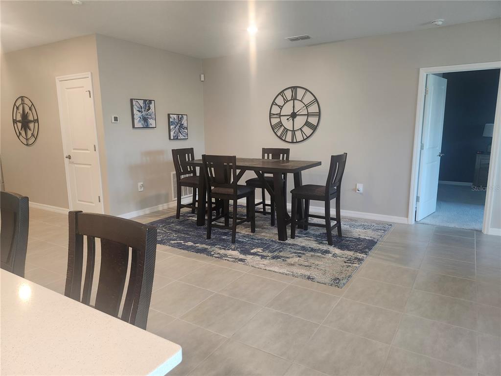 A dining area features a dark wood table and chairs set on a blue patterned rug — 1009 CALICO POINTE CIRCLE, GROVELAND, FL